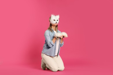 Photo of Quadrobics. Woman wearing cat mask and gloves on pink background