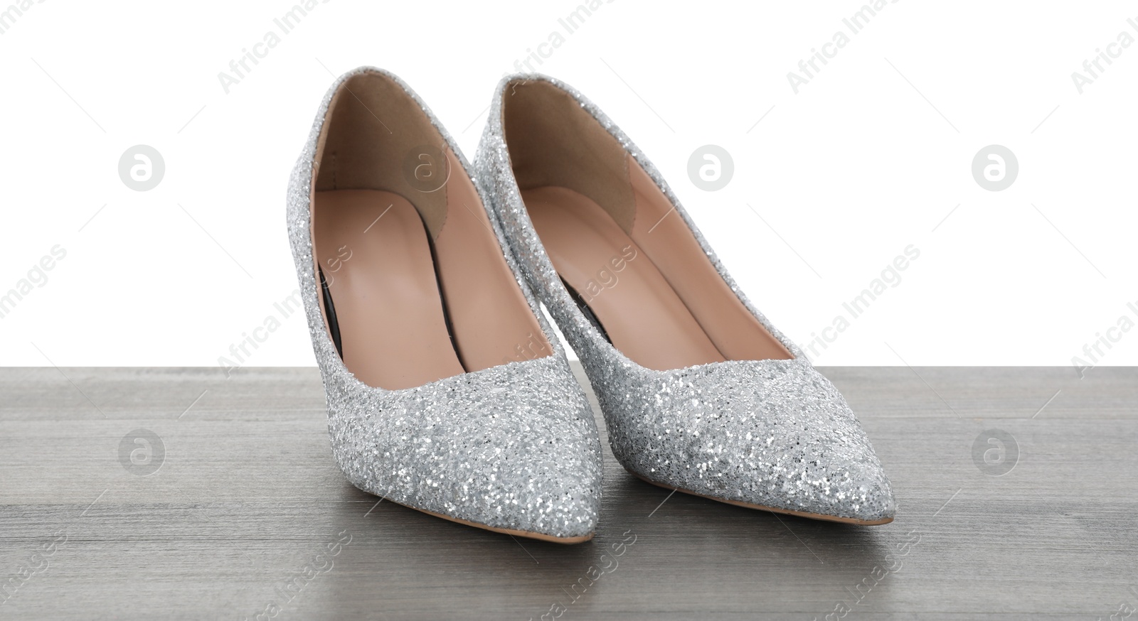 Photo of Beautiful high heeled shoes on wooden table against white background