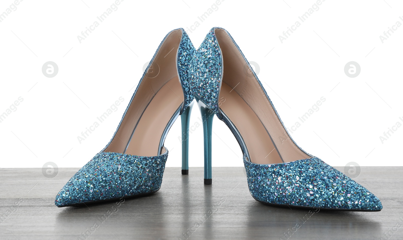 Photo of Beautiful high heeled shoes on wooden table against white background