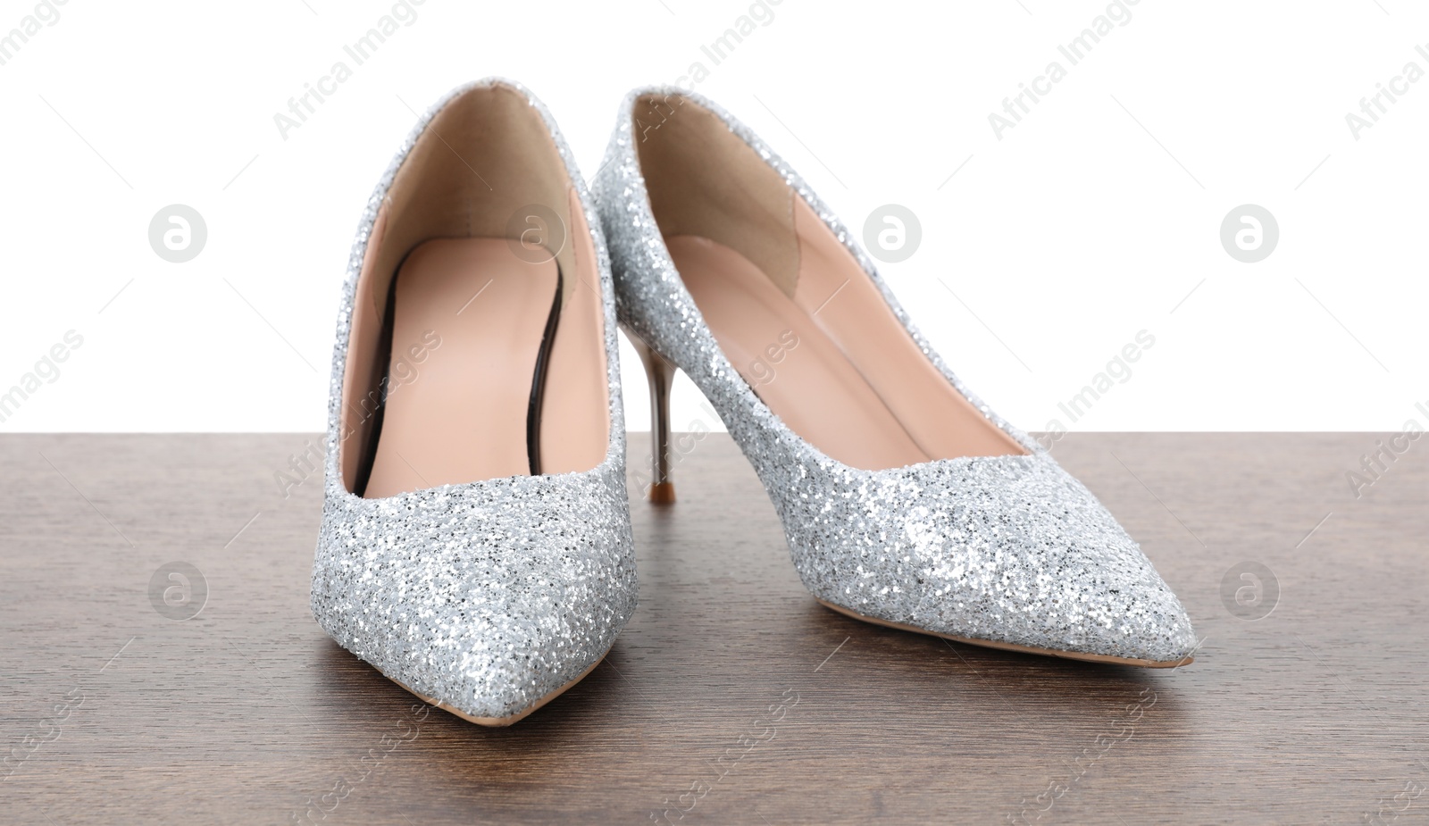 Photo of Beautiful high heeled shoes on wooden table against white background