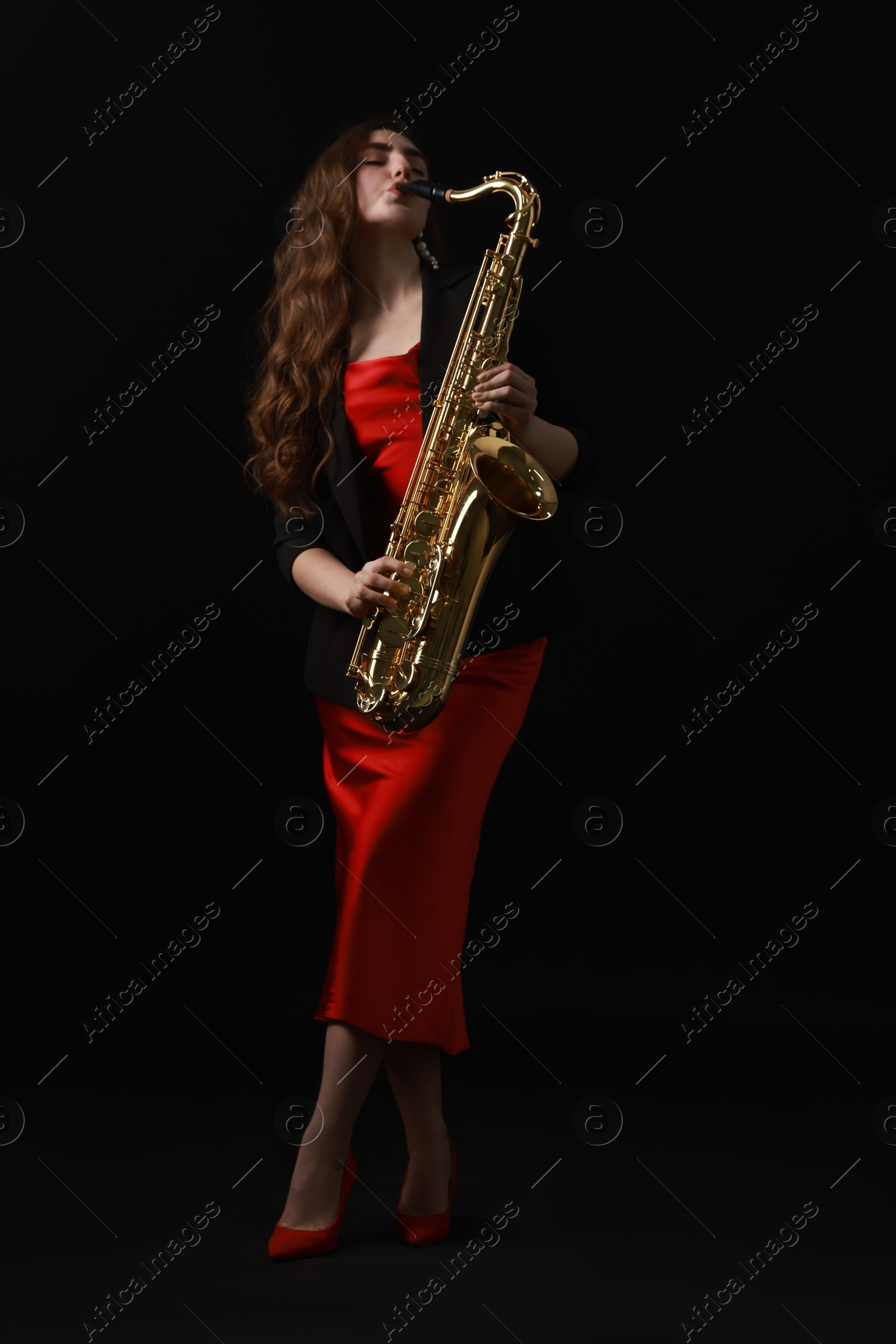 Photo of Professional musician playing saxophone on black background