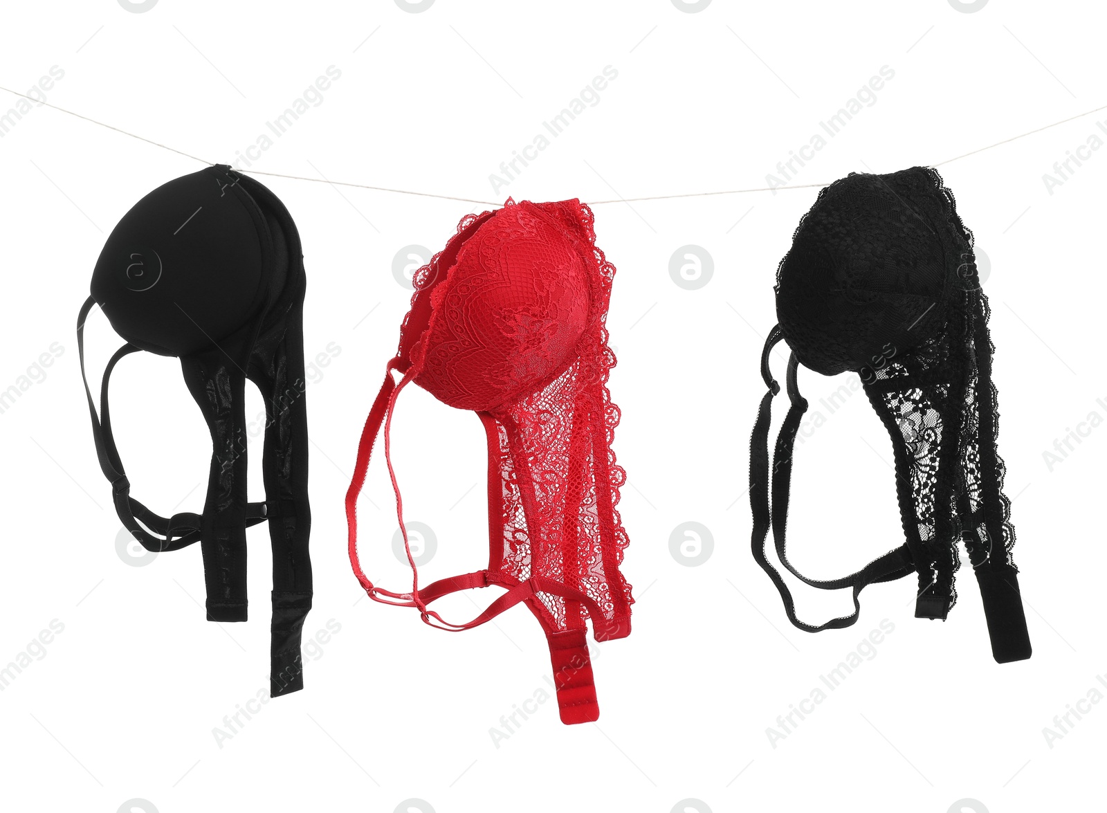 Photo of Beautiful bras hanging on rope against white background