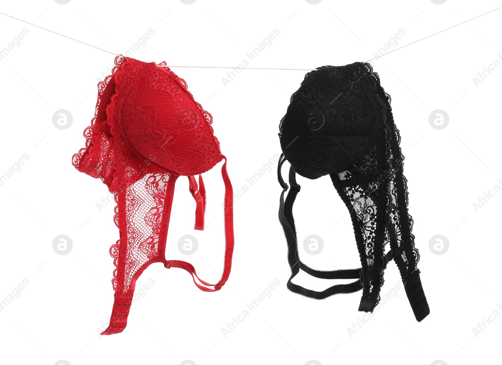 Photo of Beautiful bras hanging on rope against white background