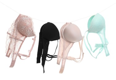 Photo of Beautiful bras hanging on rope against white background