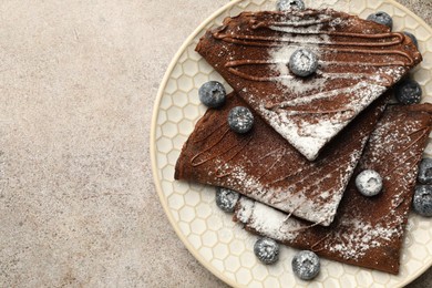 Photo of Delicious chocolate crepes with blueberries on grey table, top view. Space for text