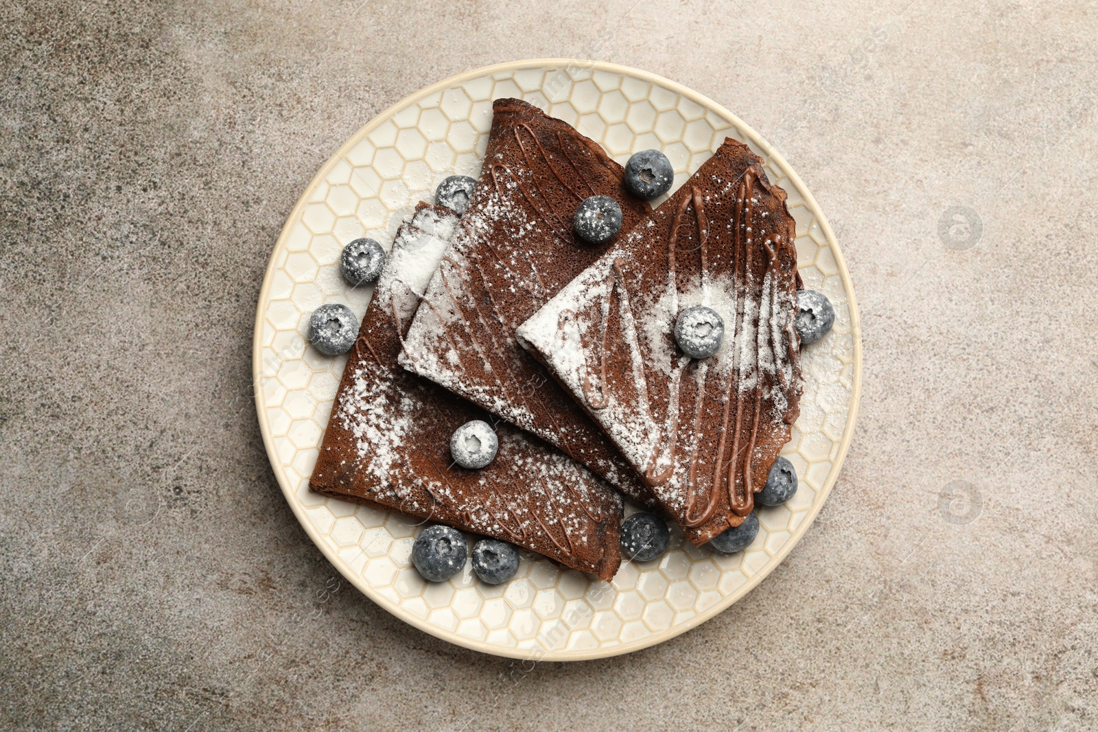 Photo of Delicious chocolate crepes with blueberries on grey table, top view