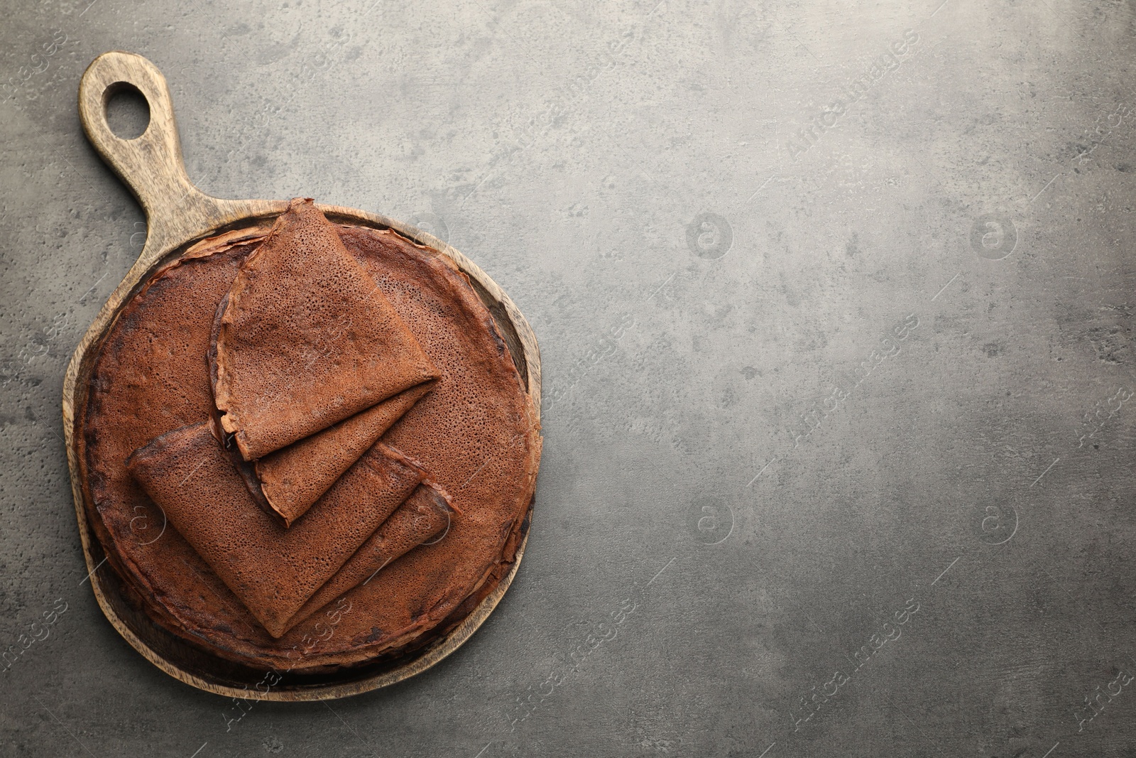 Photo of Delicious chocolate crepes on grey table, top view. Space for text