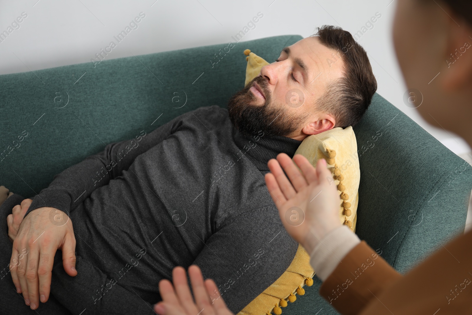 Photo of Psychologist working with patient during hypnosis session indoors, closeup