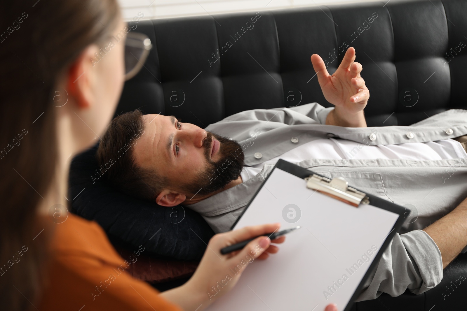 Photo of Psychologist working with patient during hypnosis session indoors