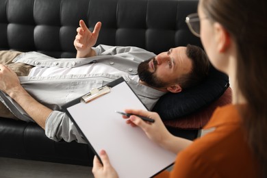 Photo of Psychologist working with patient during hypnosis session indoors