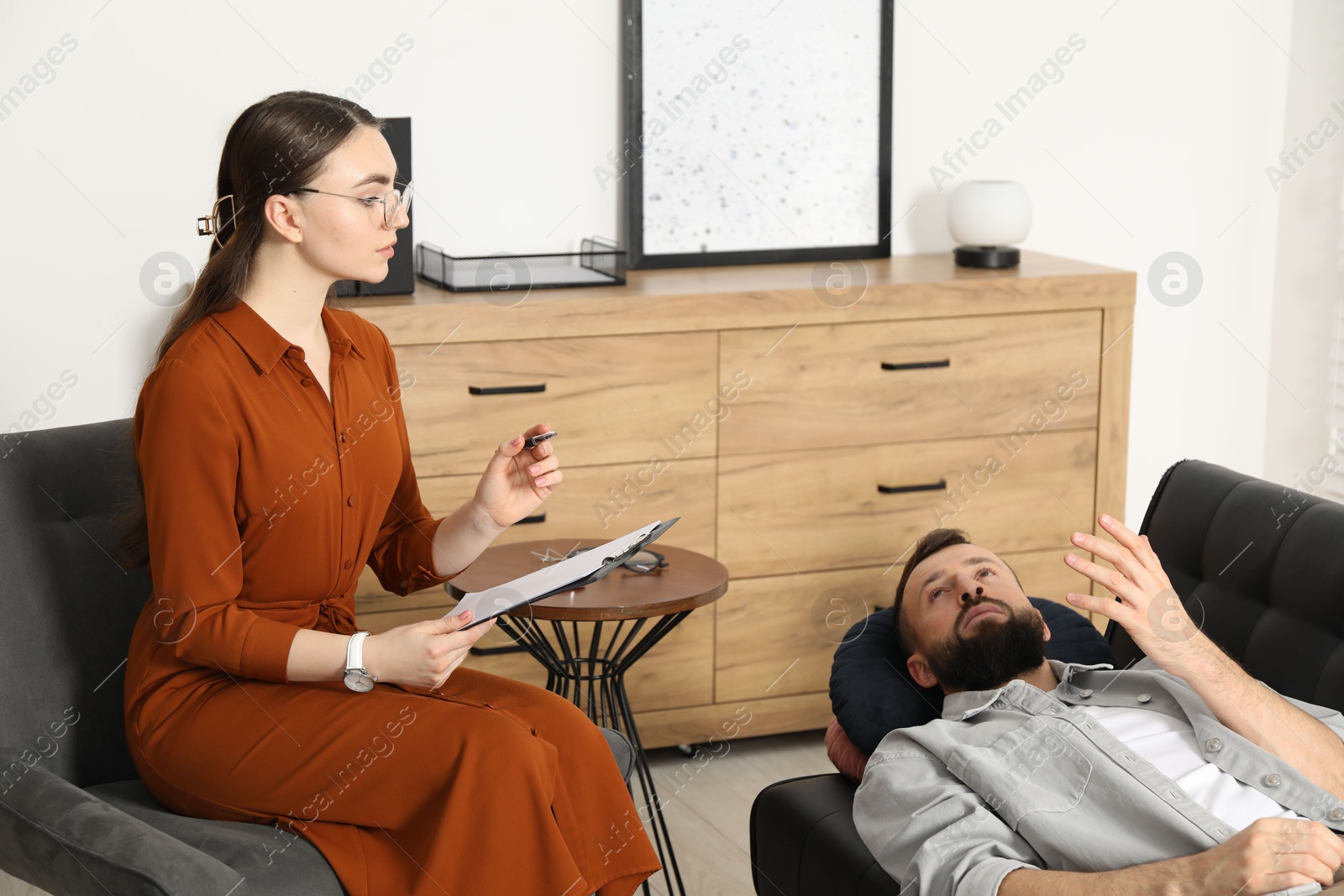 Photo of Psychologist working with patient during hypnosis session indoors