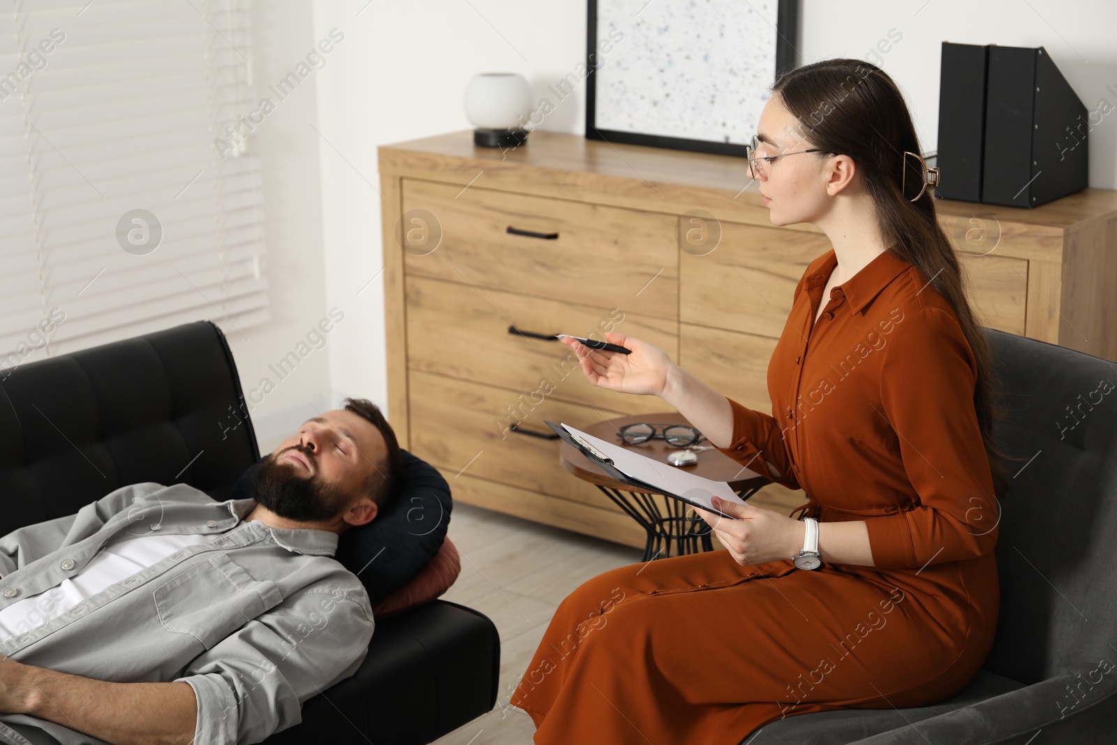 Photo of Psychologist working with patient during hypnosis session indoors