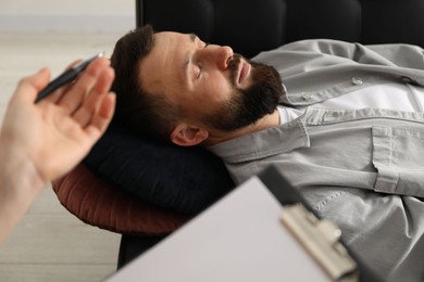 Photo of Psychologist working with patient during hypnosis session indoors, closeup