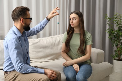 Photo of Psychologist using pendulum while working with patient during hypnosis session indoors