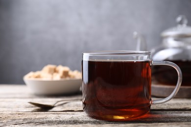 Photo of Aromatic black tea in cup on wooden table, closeup