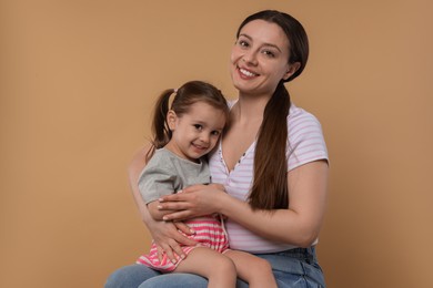 Photo of Portrait of happy mother and her cute little daughter on beige background