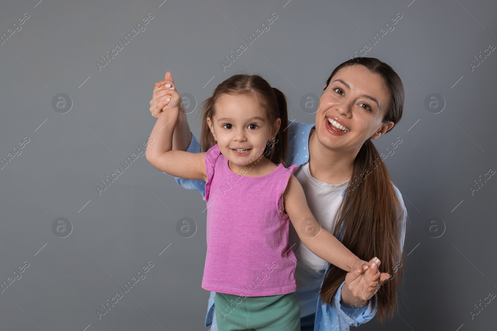 Photo of Portrait of happy mother and her cute little daughter on grey background