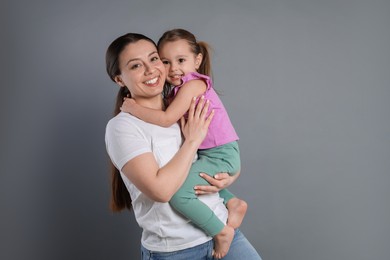 Photo of Portrait of happy mother and her cute little daughter on grey background, space for text