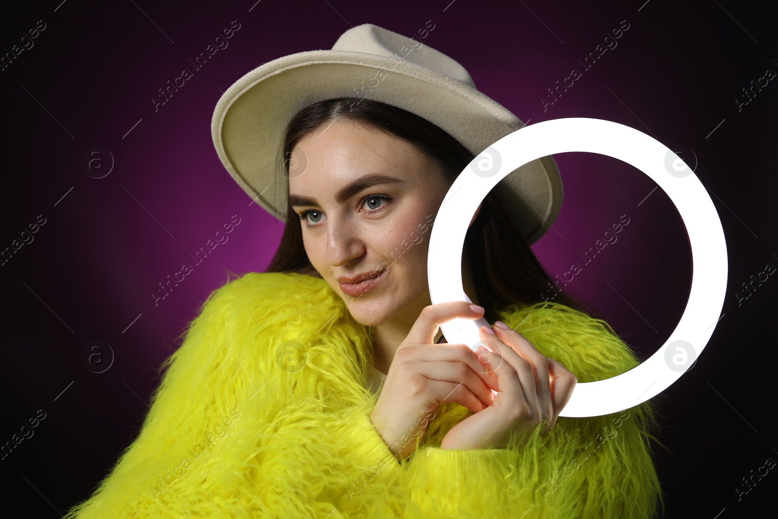 Photo of Stylish woman with ring lamp on dark purple background