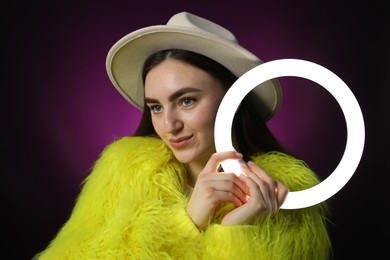 Photo of Stylish woman with ring lamp on dark purple background