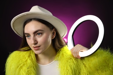 Photo of Stylish woman with ring lamp on dark purple background