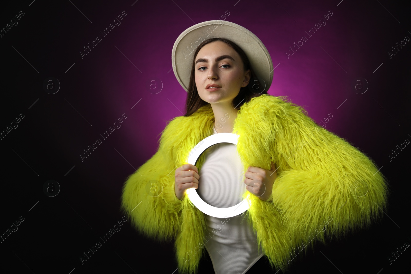 Photo of Stylish woman with ring lamp on dark purple background, space for text