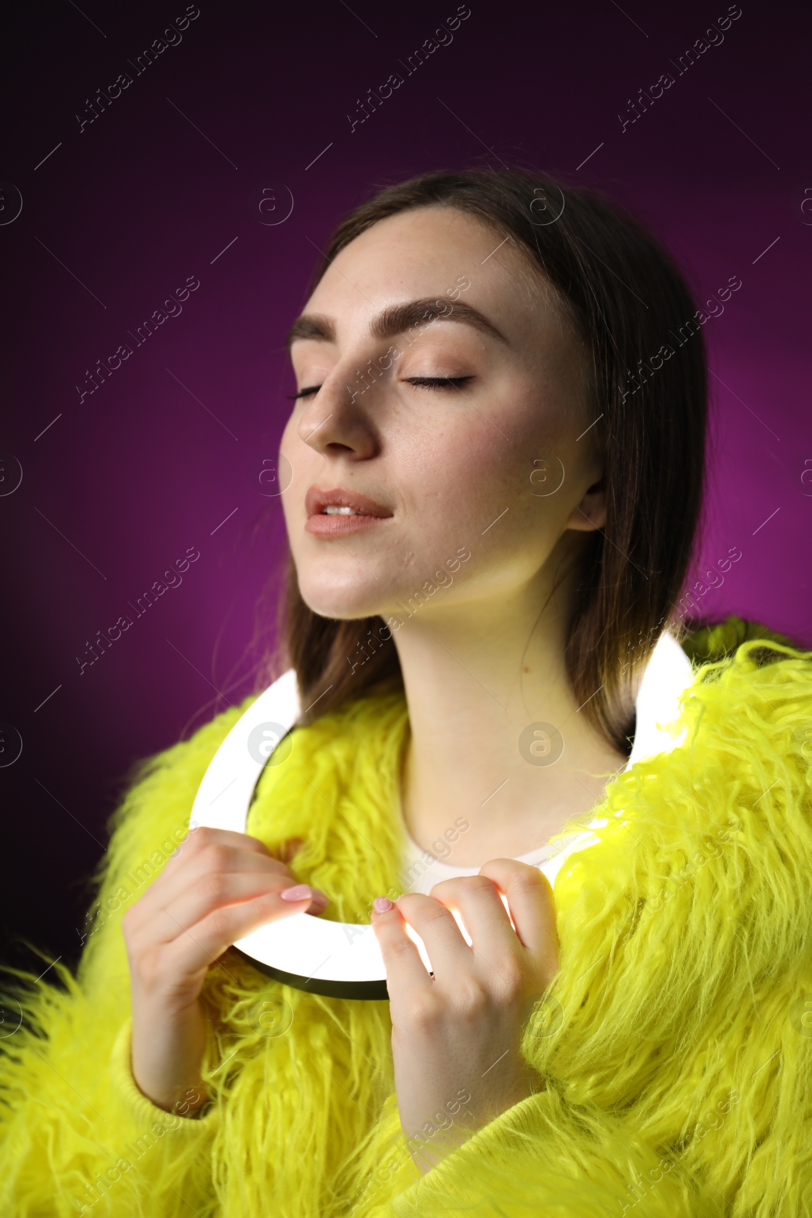 Photo of Stylish woman with ring lamp on dark purple background