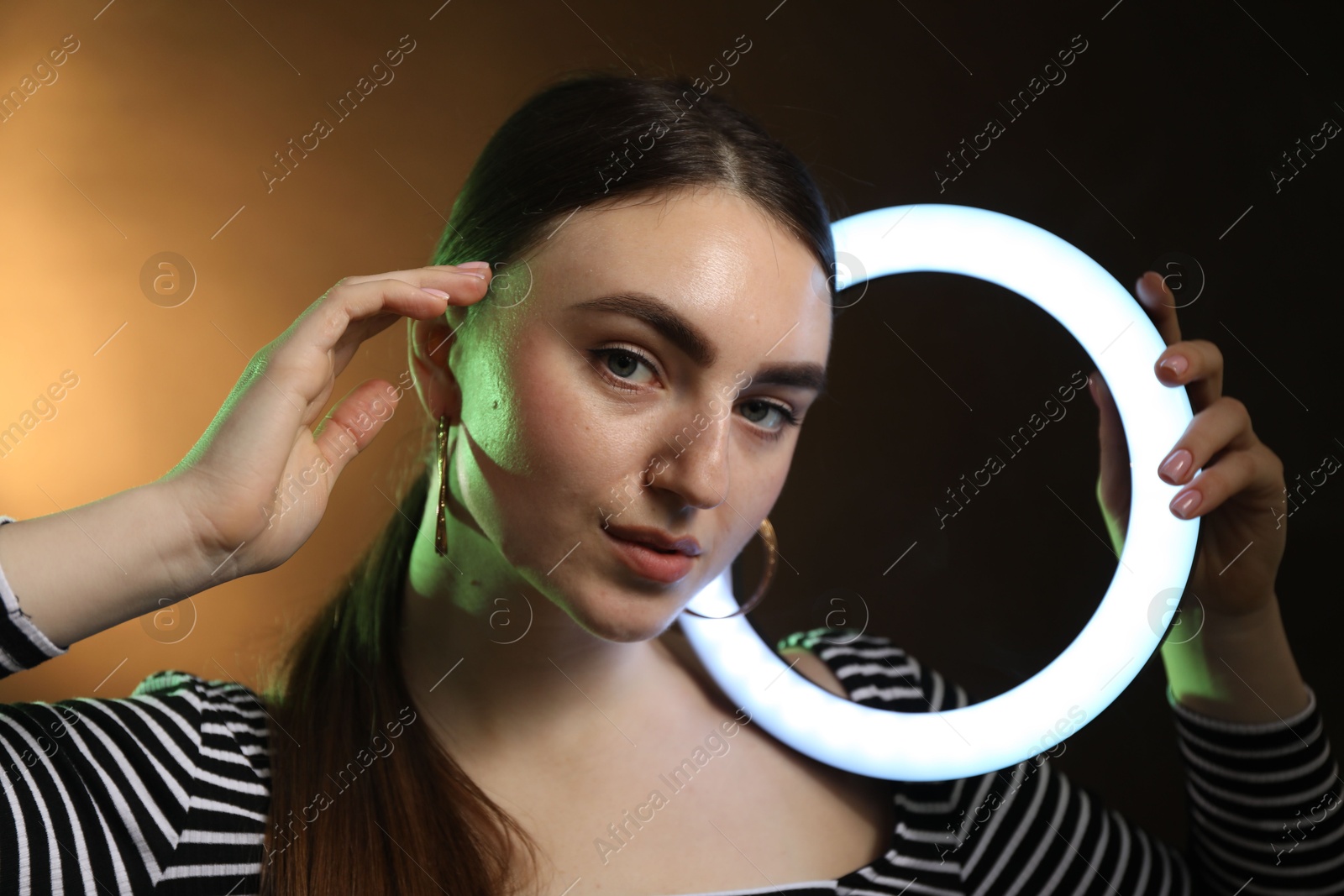 Photo of Beautiful woman with ring lamp on dark background