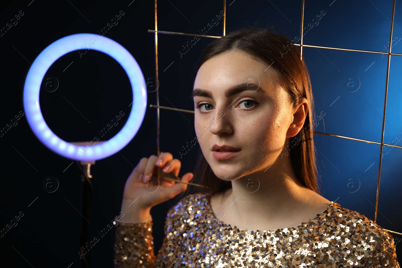 Photo of Beautiful woman with grid and ring lamp on dark blue background