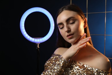 Photo of Beautiful woman with grid and ring lamp on dark blue background