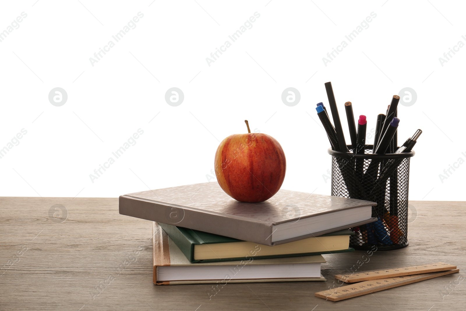 Photo of Doing homework. Notebooks, apple and different stationery on wooden table against white background