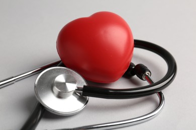 Photo of Cardiology. Stethoscope and red decorative heart on light gray background, closeup