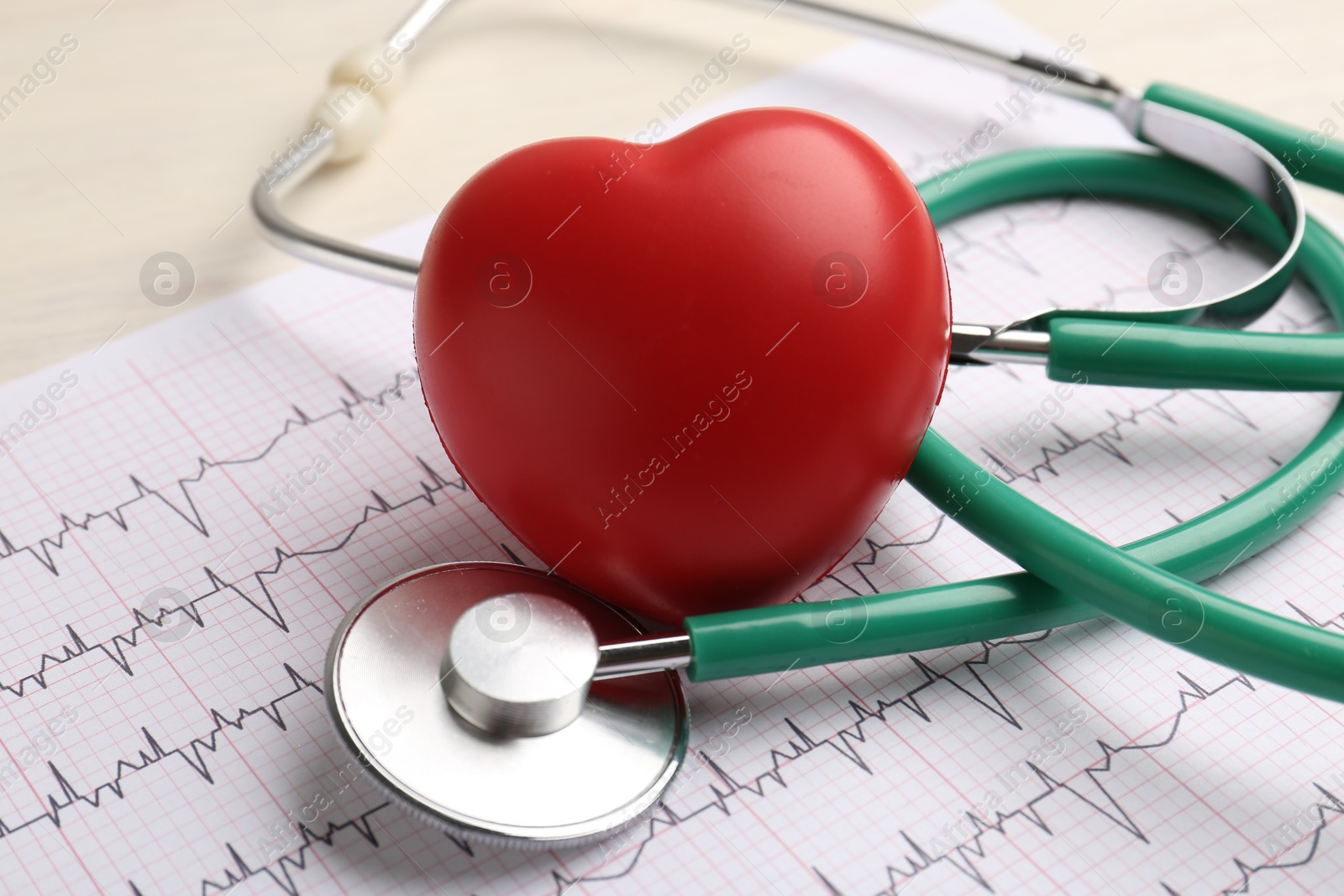 Photo of Cardiology. Stethoscope, cardiogram and red decorative heart on light table, closeup