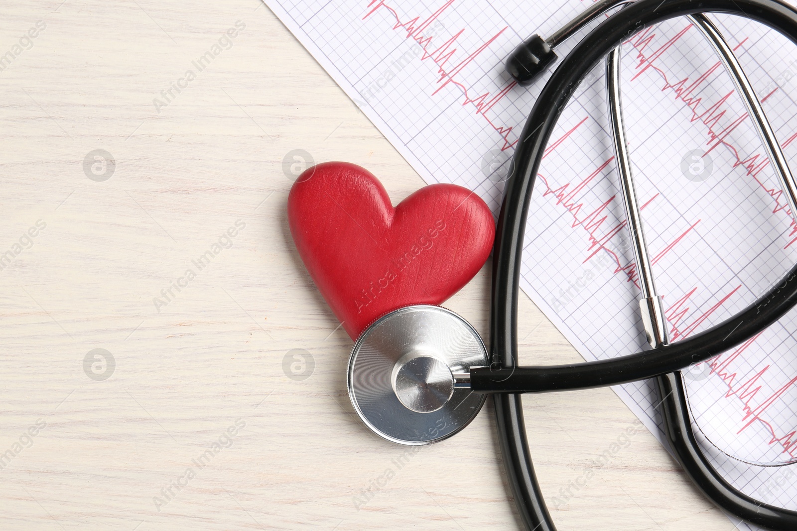 Photo of Cardiology. Stethoscope, cardiogram and red decorative heart on light wooden table, flat lay. Space for text