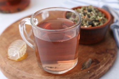 Photo of Delicious herbal tea, honey and dry leaves on white table, closeup