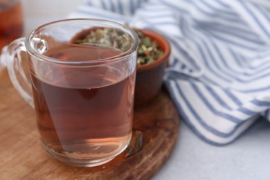 Photo of Delicious herbal tea and dry leaves on white table, closeup. Space for text