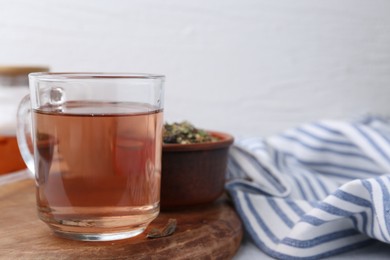 Photo of Delicious herbal tea and dry leaves on white table. Space for text