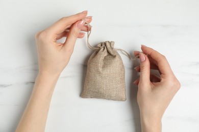 Photo of Woman with burlap bag at white marble table, top view