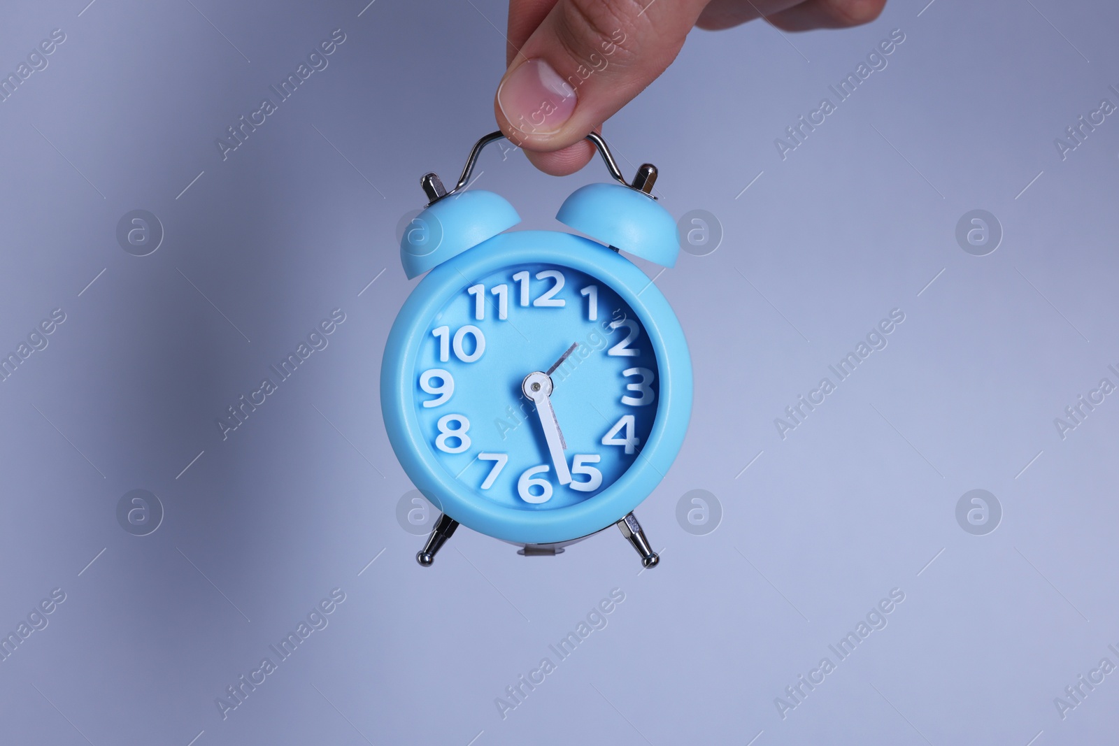 Photo of Man with light blue alarm clock on grey background, closeup