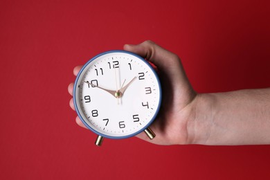 Photo of Man with alarm clock on red background, closeup