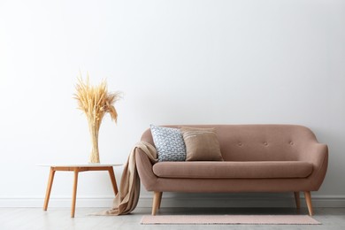 Image of Sofa in mocha mousse shade and decor indoors. Interior with trendy color of 2025 year