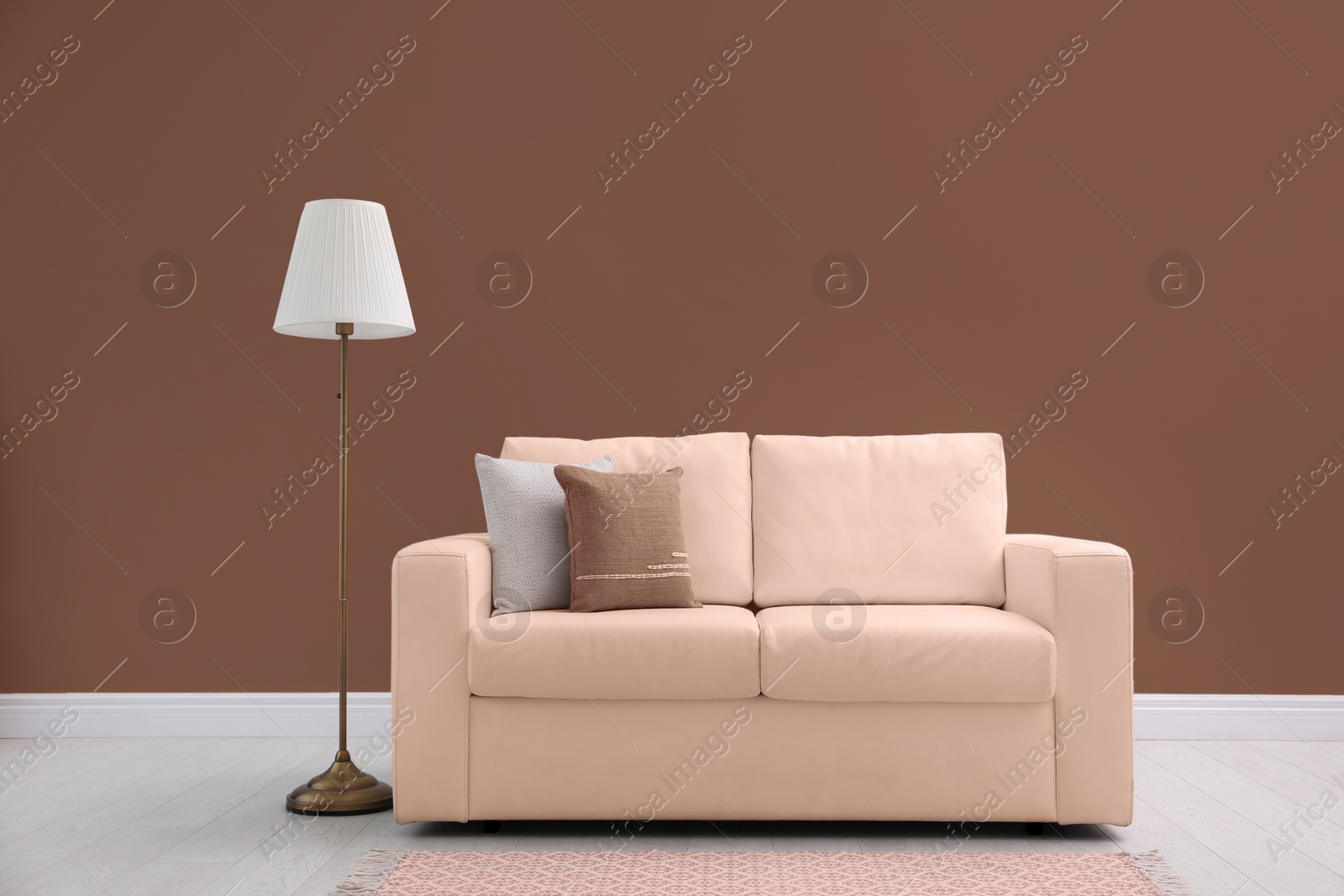 Image of Beige sofa and floor lamp near mocha mousse shade wall indoors. Interior with trendy color of 2025 year