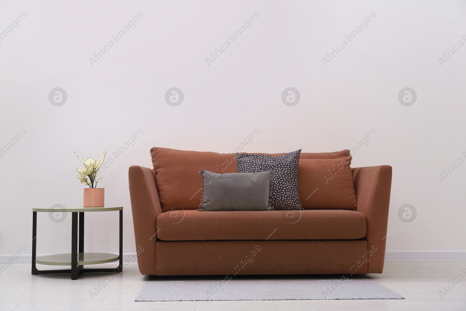 Image of Sofa in mocha mousse shade and decor indoors. Interior with trendy color of 2025 year