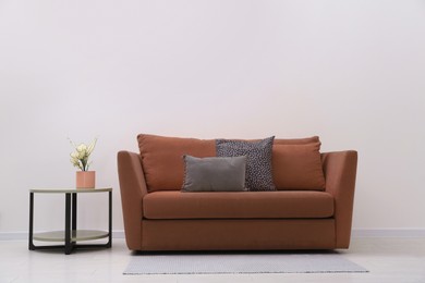 Image of Sofa in mocha mousse shade and decor indoors. Interior with trendy color of 2025 year