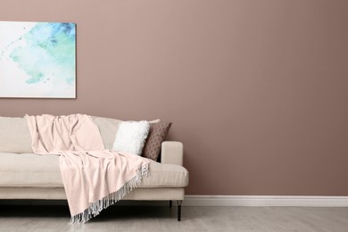 Image of Beige sofa near wall in mocha mousse shade. Trendy color of 2025 year