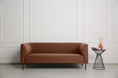 Image of Sofa in mocha mousse shade and decor indoors. Interior with trendy color of 2025 year