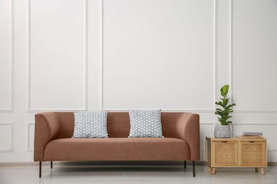 Image of Sofa in mocha mousse shade and house plant indoors. Interior with trendy color of 2025 year