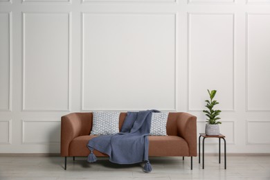 Image of Sofa in mocha mousse shade and house plant indoors. Interior with trendy color of 2025 year