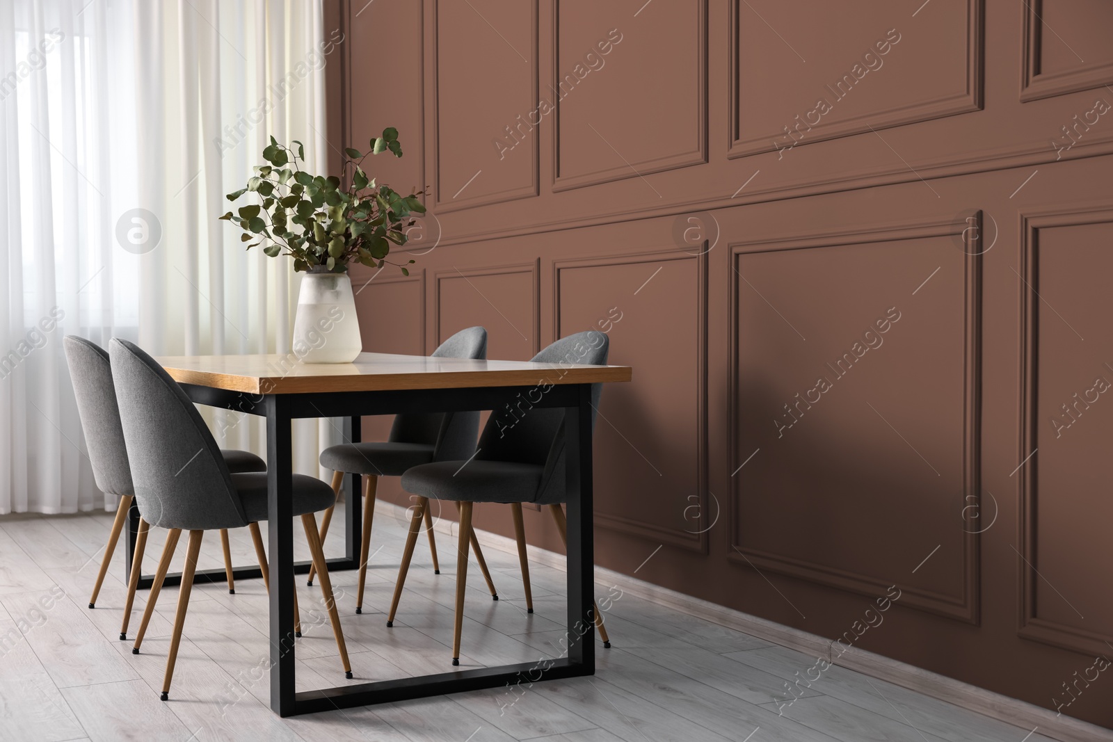 Image of Table and chairs near mocha mousse shade wall indoors. Interior with trendy color of 2025 year