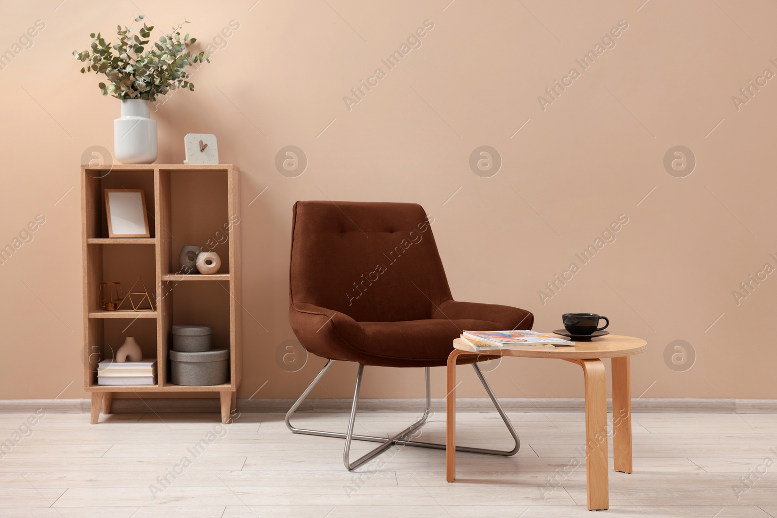 Image of Armchair in mocha mousse shade, table and shelving unit indoors. Cozy living room interior with color of 2025 year